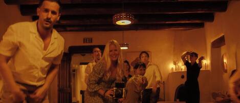 A group of people in a dimly lit room with a wooden ceiling and a hanging light fixture.