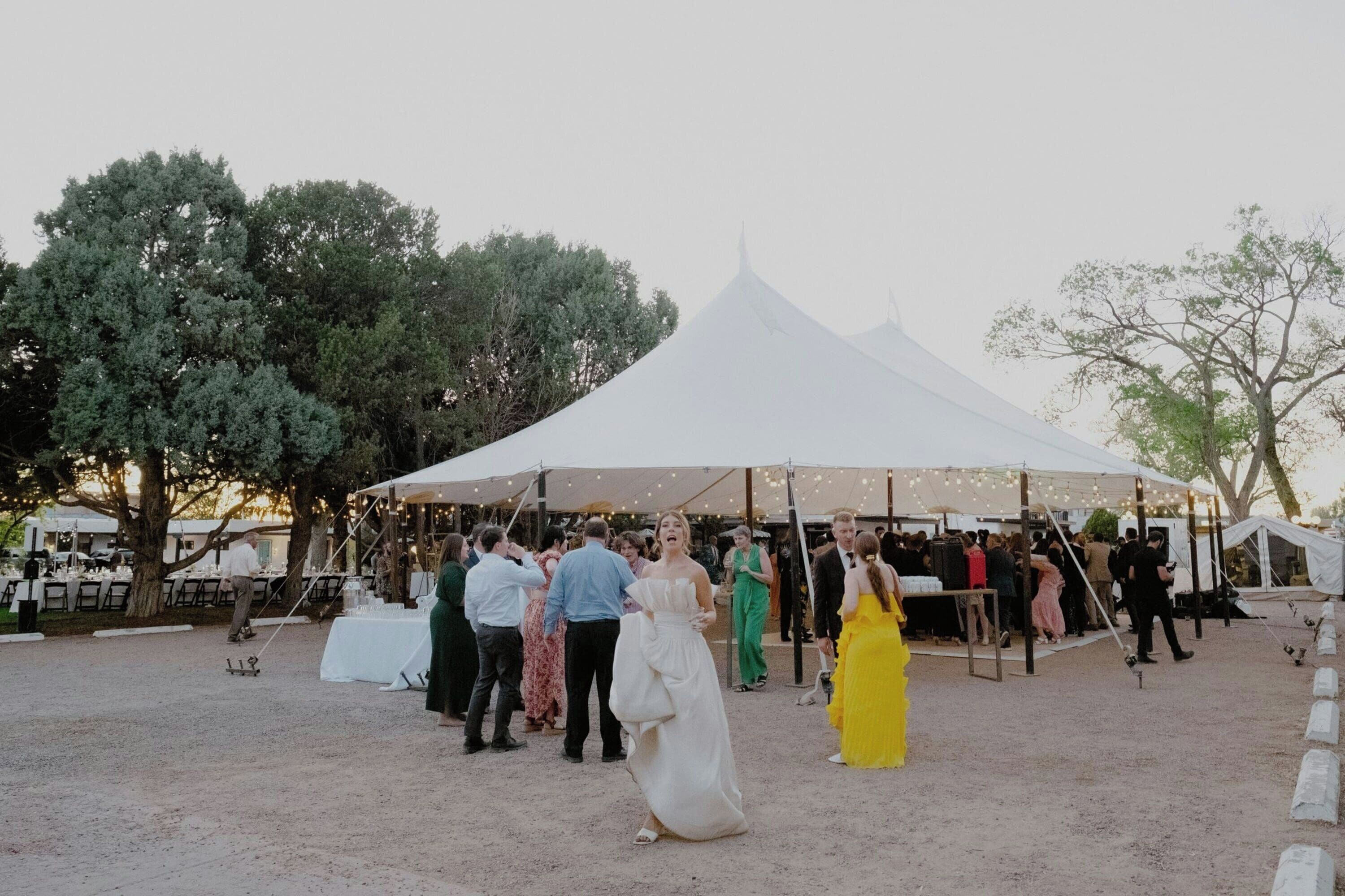 An outdoor event with a tent, tables, and chairs set up for guests.