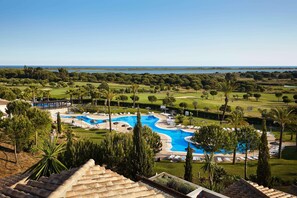 A resort with a large swimming pool, palm trees, and a view of the ocean.