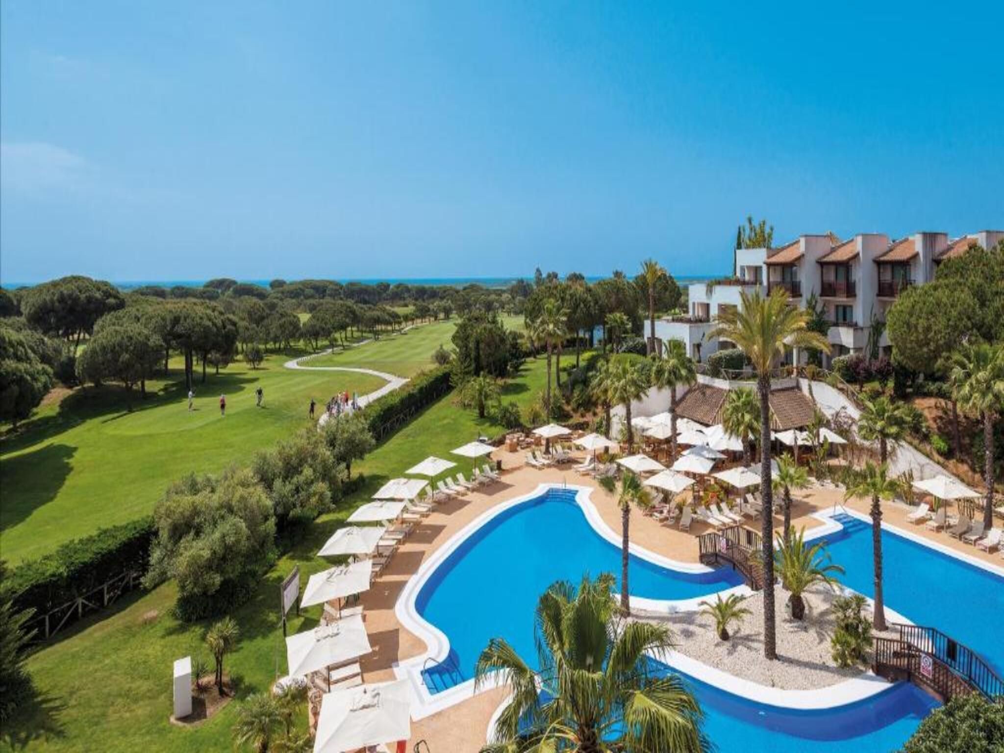 Un resort con piscina, sillas de descanso y vistas al océano.