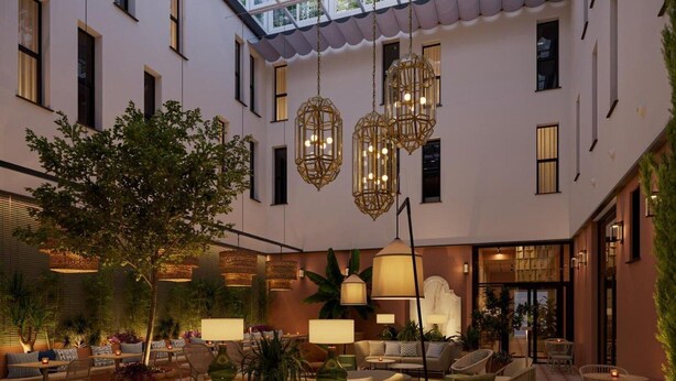 A spacious indoor courtyard with seating areas, hanging lights, and a large tree. - Montecarlo (Granada)