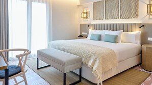 A modern hotel room with a large bed, a bedside table, a chair, and a view of the outdoors. - Montecarlo (Granada)