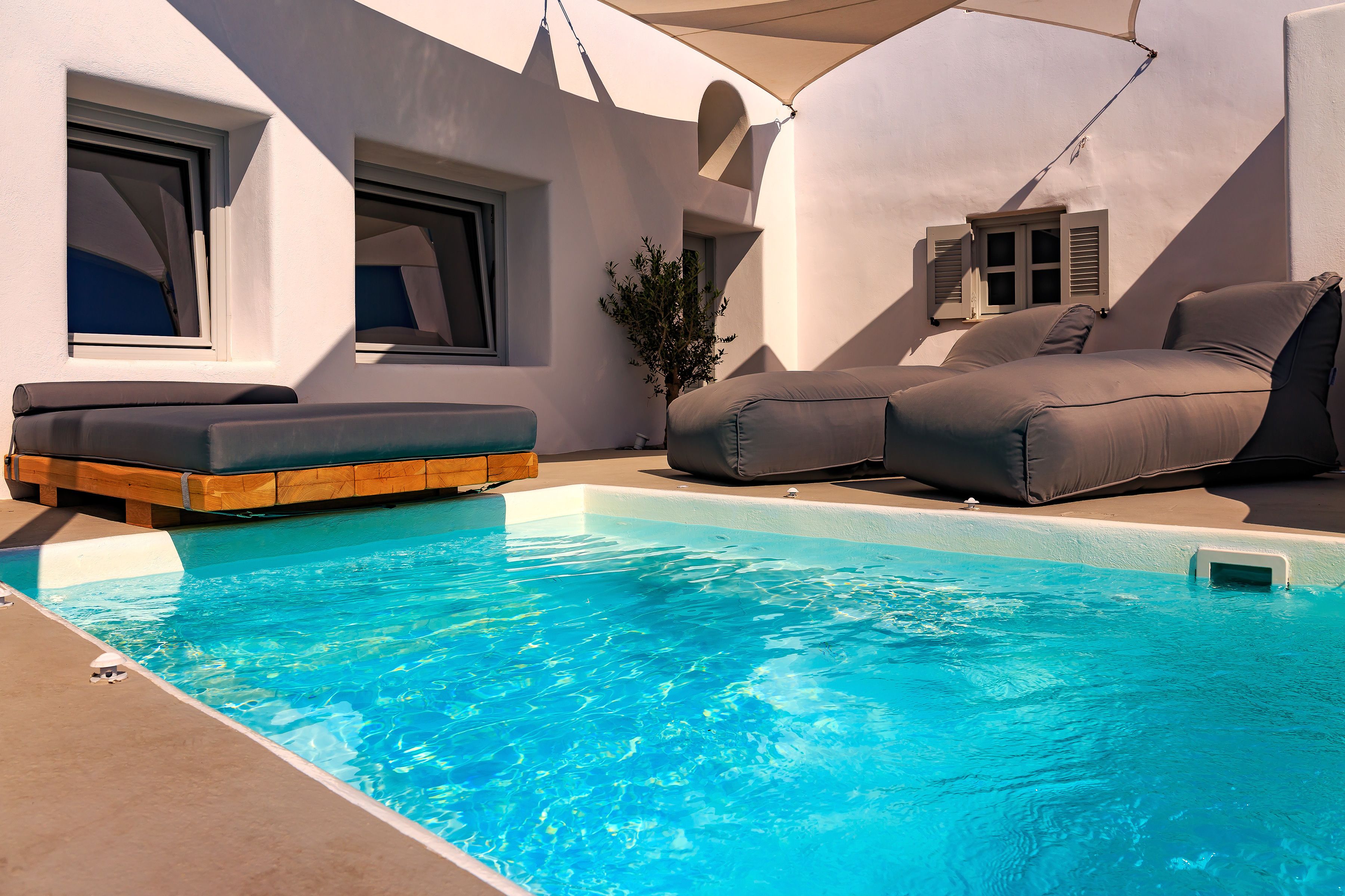 A poolside area with a pool, a sofa, and a small plant.