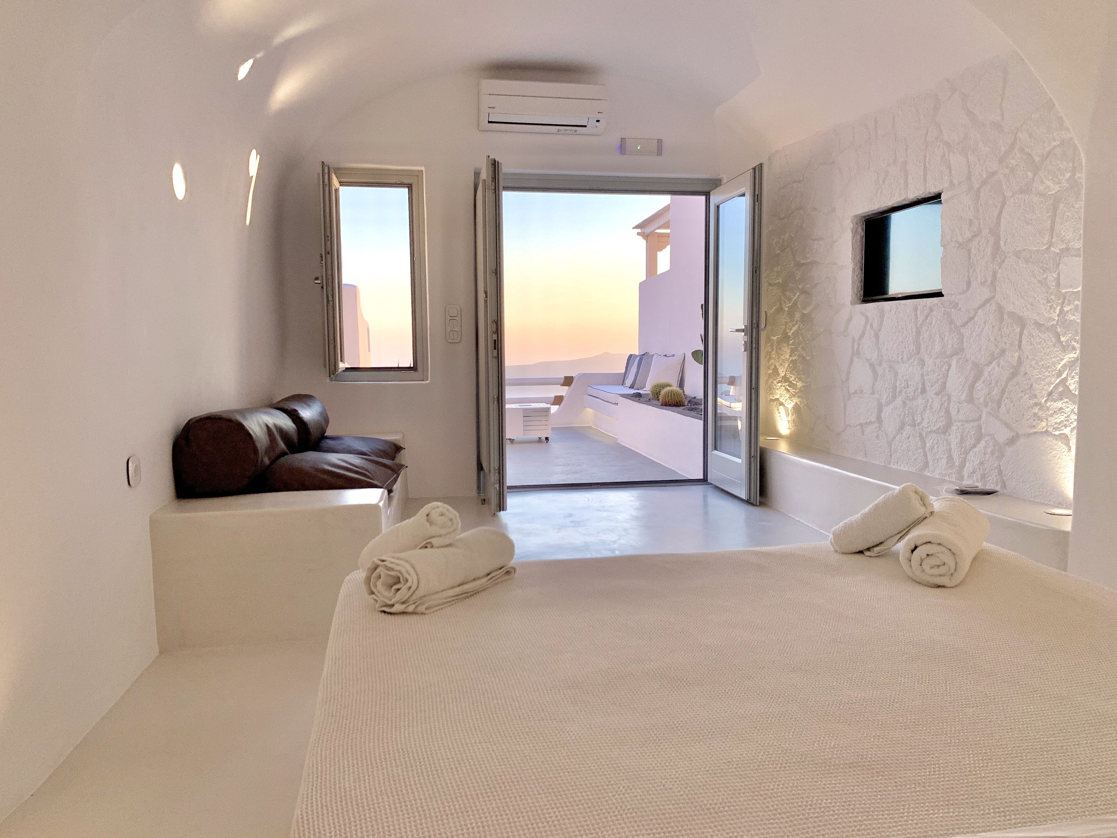 A modern bedroom with a large bed, a sofa, and a view of the outside.