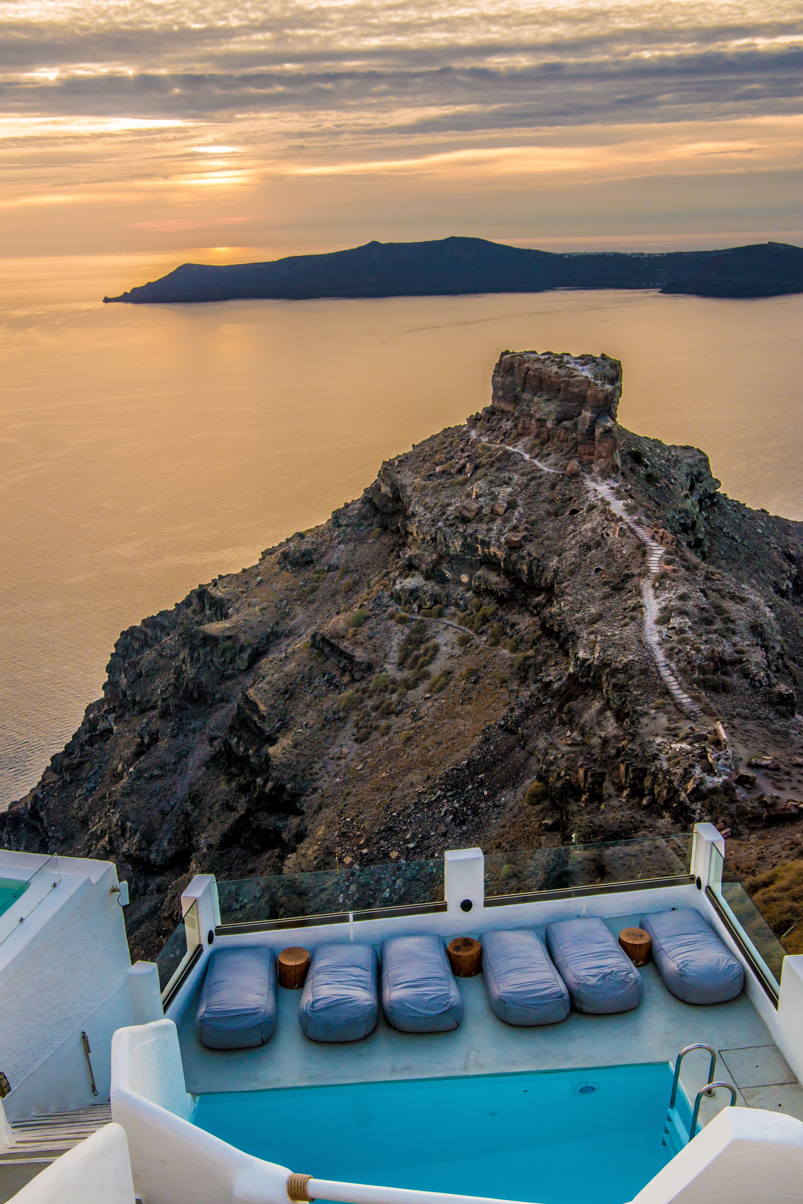 A boat with a pool and seating area, overlooking a rocky coastline and calm sea.