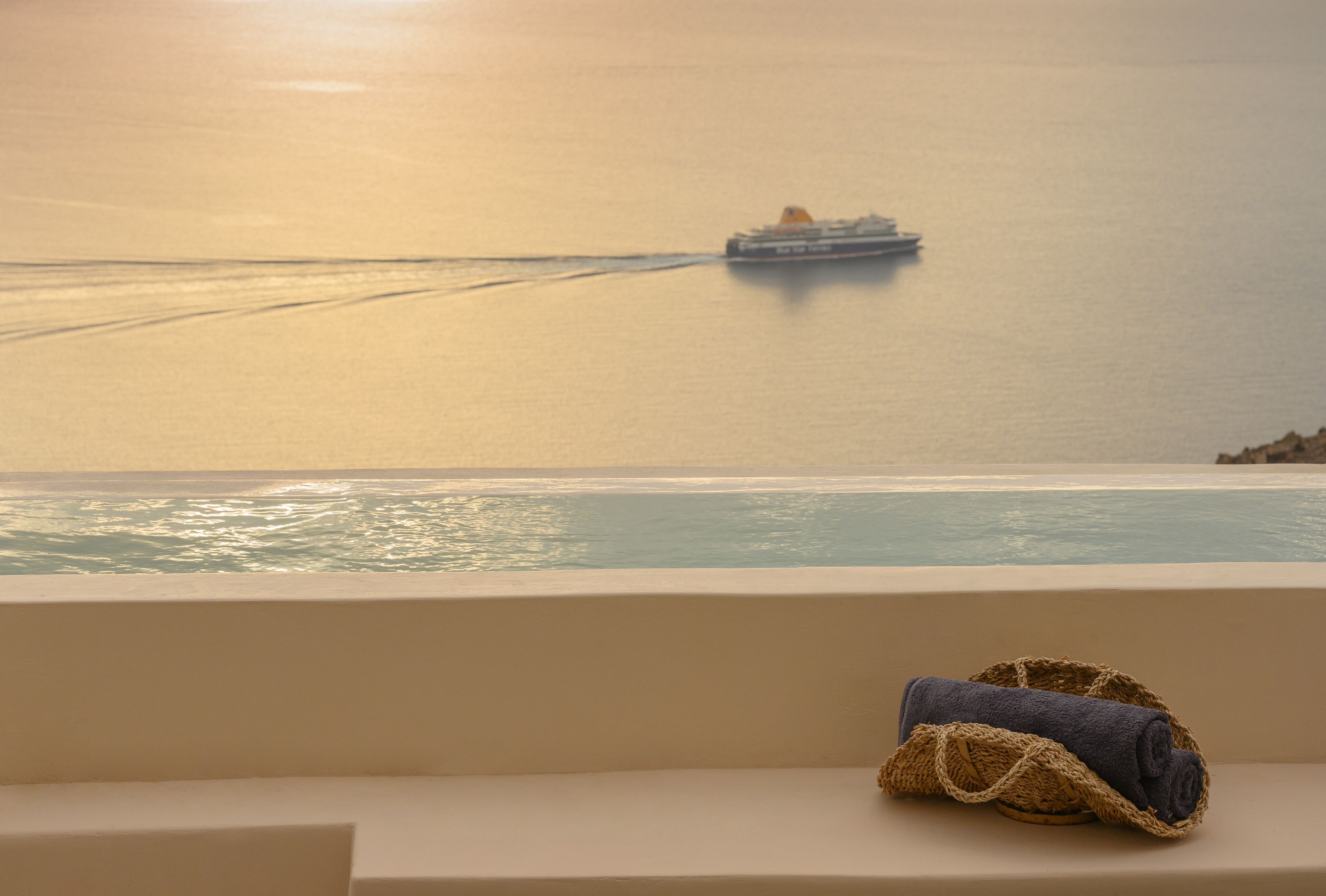 Blick von einem Balkon auf ein ruhiges Meer mit einem Schiff in der Ferne.