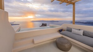 Ein moderner Sitzbereich im Freien mit Blick auf den Sonnenuntergang über dem Meer.