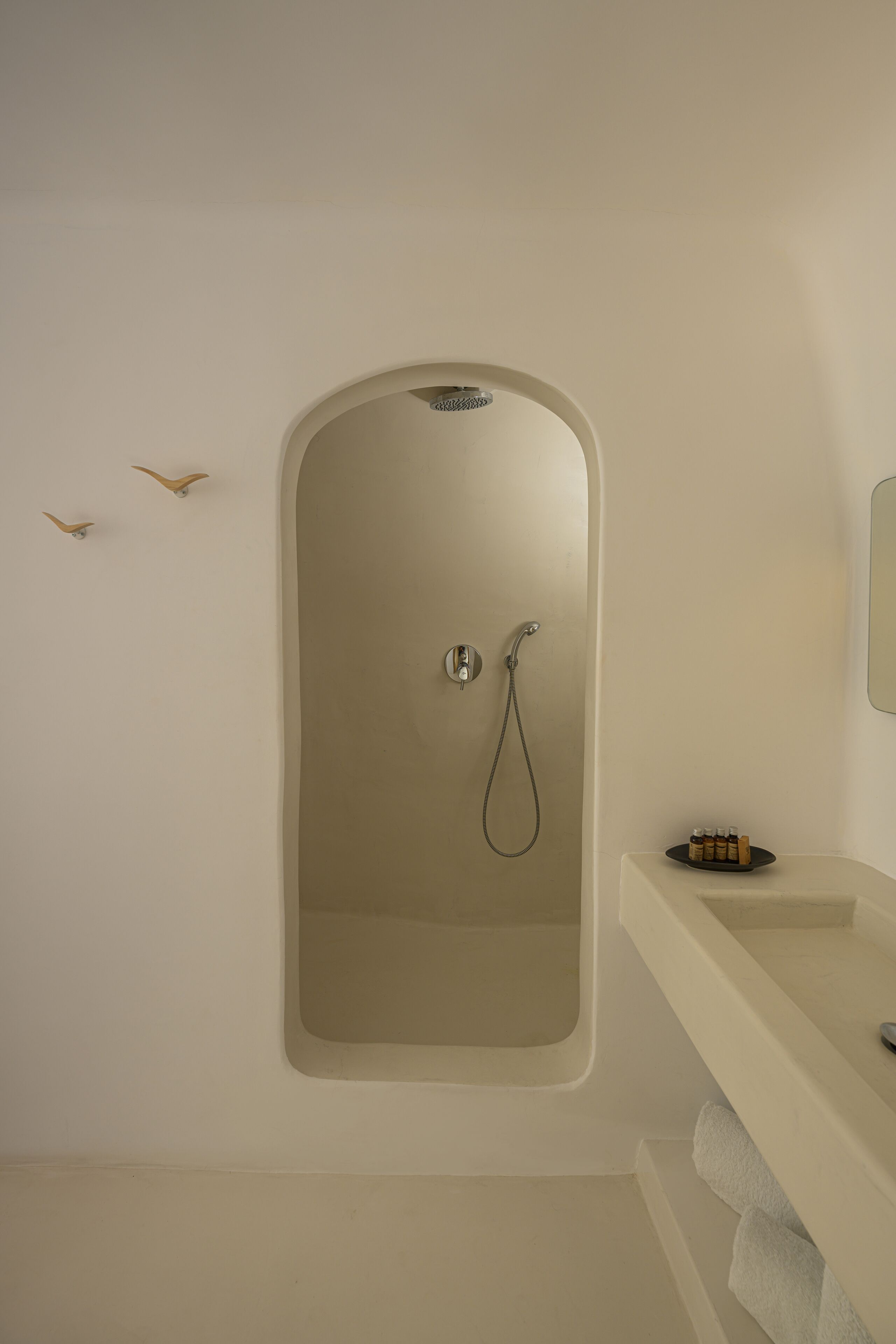 A bathroom with a built-in shower, a vanity with a mirror, and a towel rack.