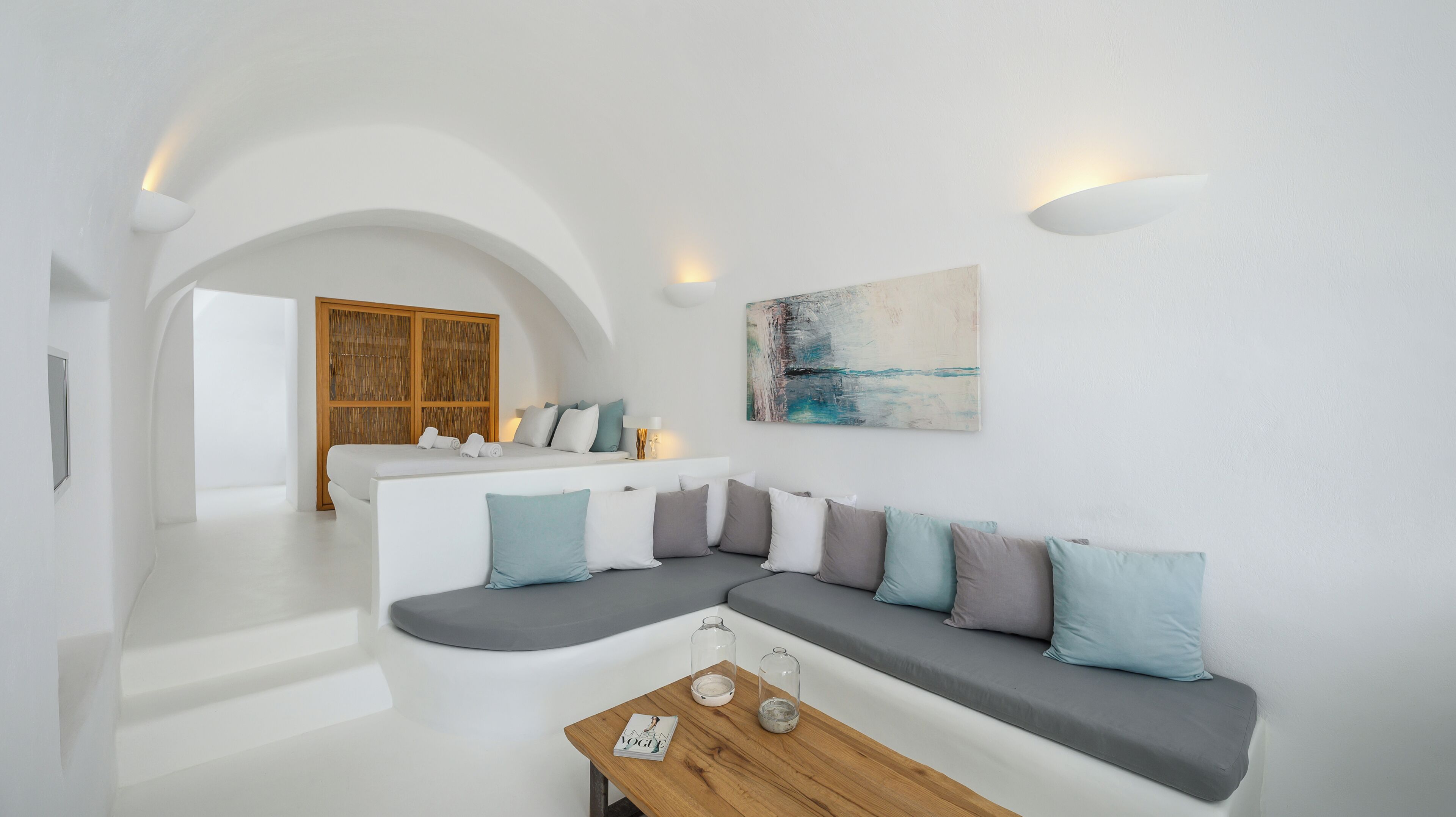A modern living room with a grey sectional sofa, a wooden coffee table, and a large abstract painting on the wall.