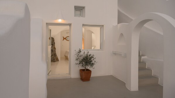 A hallway with white walls, a potted plant, and a staircase. - Hotel Sunny Villas (Santorini)