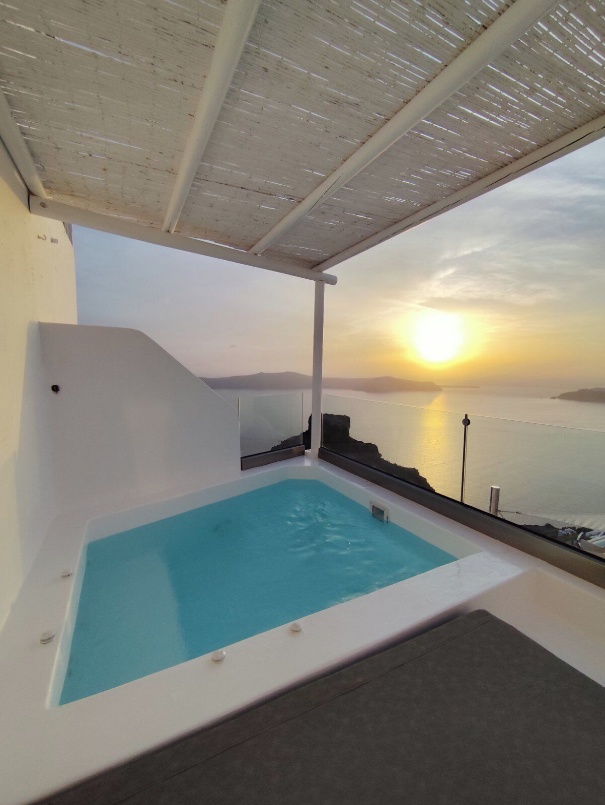 A private hot tub with a view of the sunset over the sea.