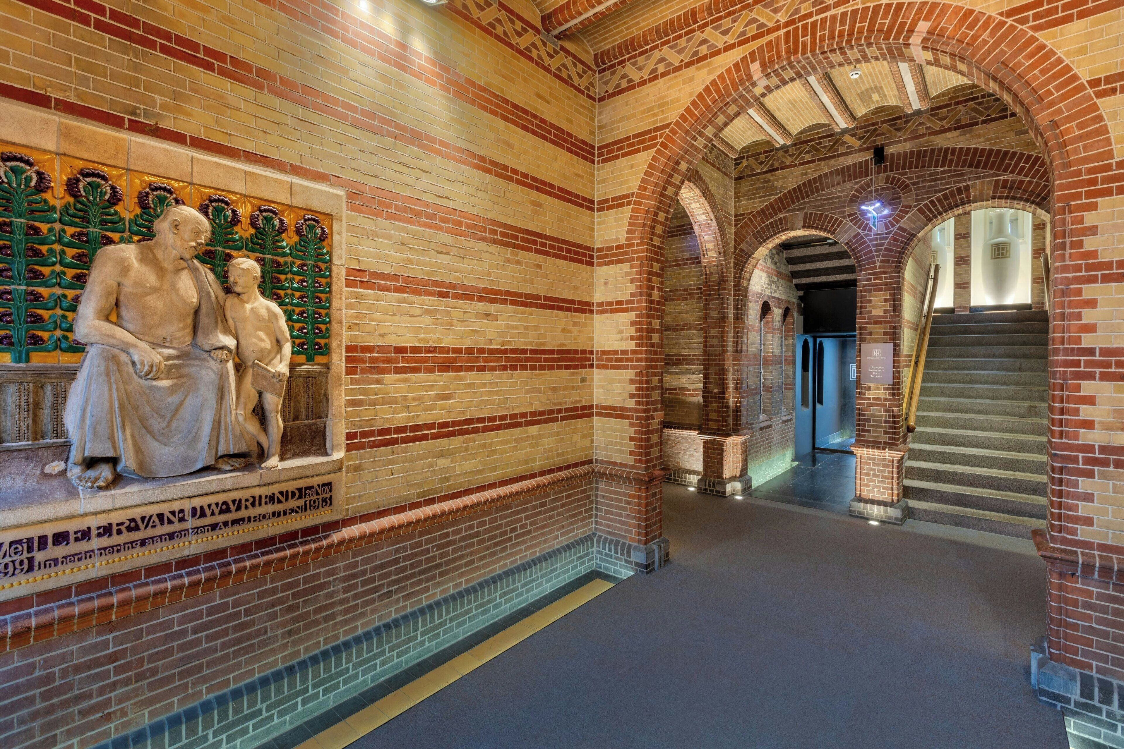 A corridor with brick walls, a statue, and a staircase.