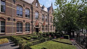 A historic building with a symmetrical facade, large windows, and a well-maintained garden with hedges and a tree. - The College Hotel Amsterdam, Autograph Collection (Amsterdam)