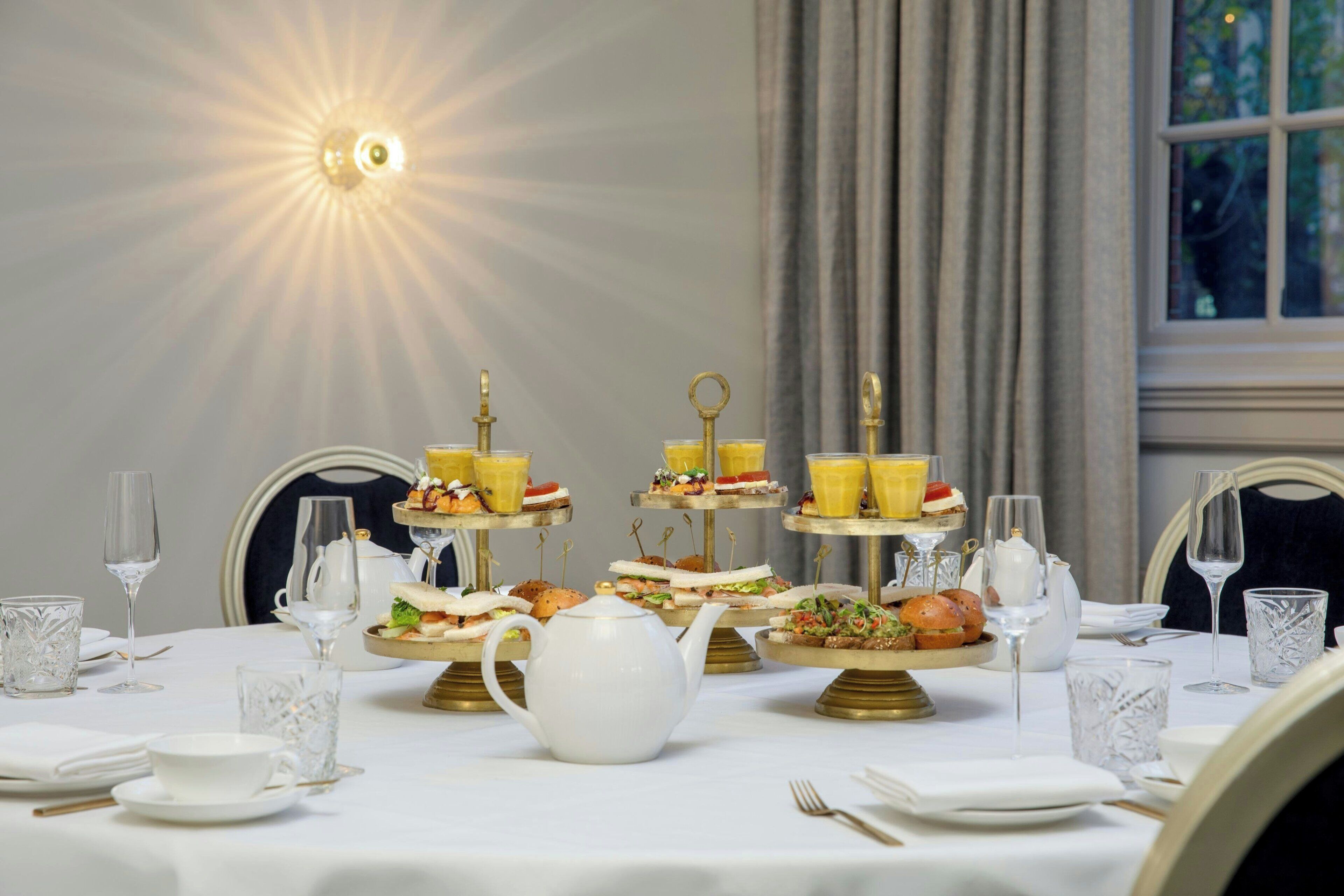 Une table à manger dressée avec une nappe blanche, de nombreux plats présentés en étages et de la verrerie.