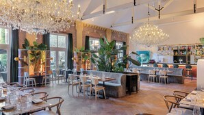 A spacious restaurant with high ceilings, large windows, and a bar area. - The College Hotel Amsterdam, Autograph Collection (Amsterdam)