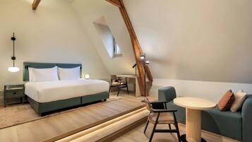 A modern loft bedroom with a bed, desk, and seating area.