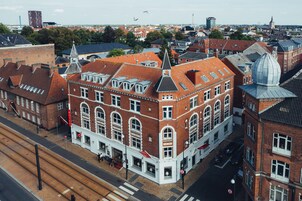 En historisk bygning med et markant tårn og en kuppel, med store vinduer og en indgang i hjørnet.