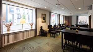 A hotel room with a large window, a radiator, a sofa, a table, and a chair. - Milling Hotel Ansgar (Odense)