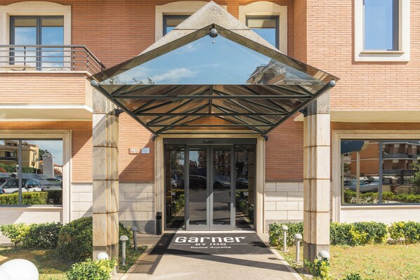 L'ingresso di un hotel con portico, una targa e una vista libera sulla strada.