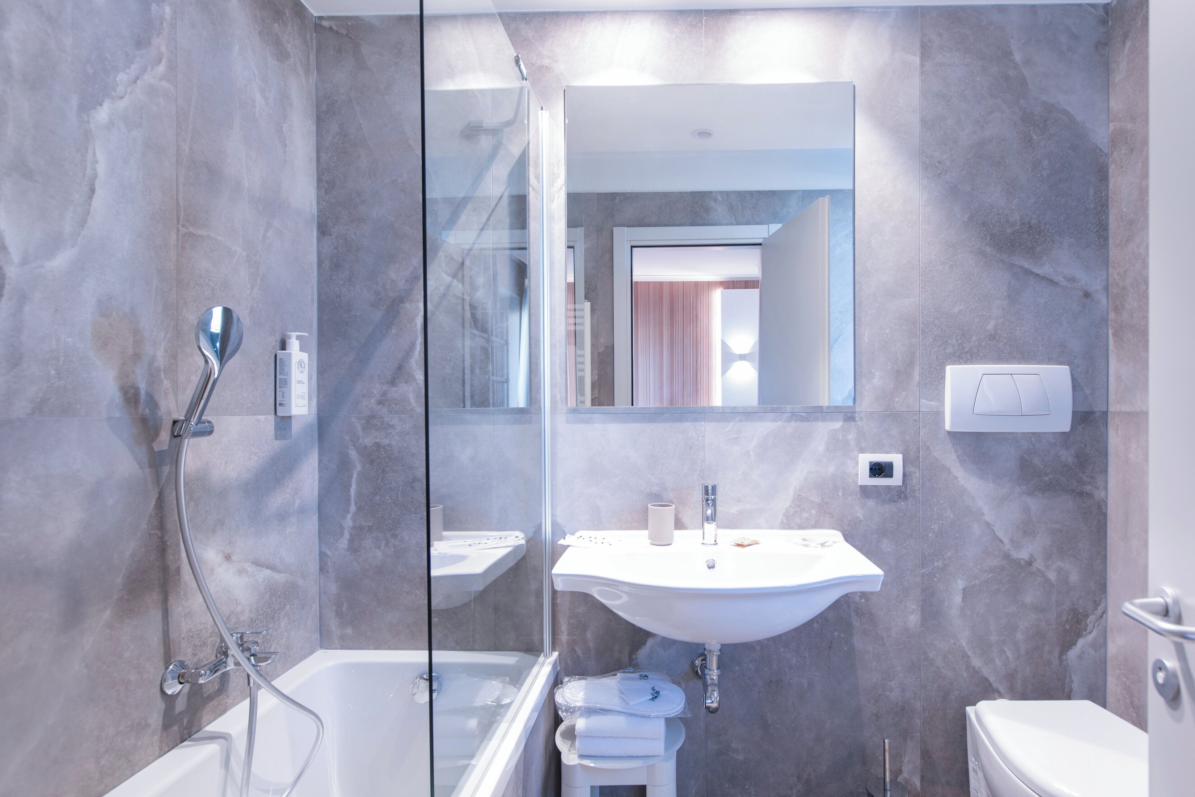 A modern bathroom with a glass-enclosed shower, a white sink, and a toilet.