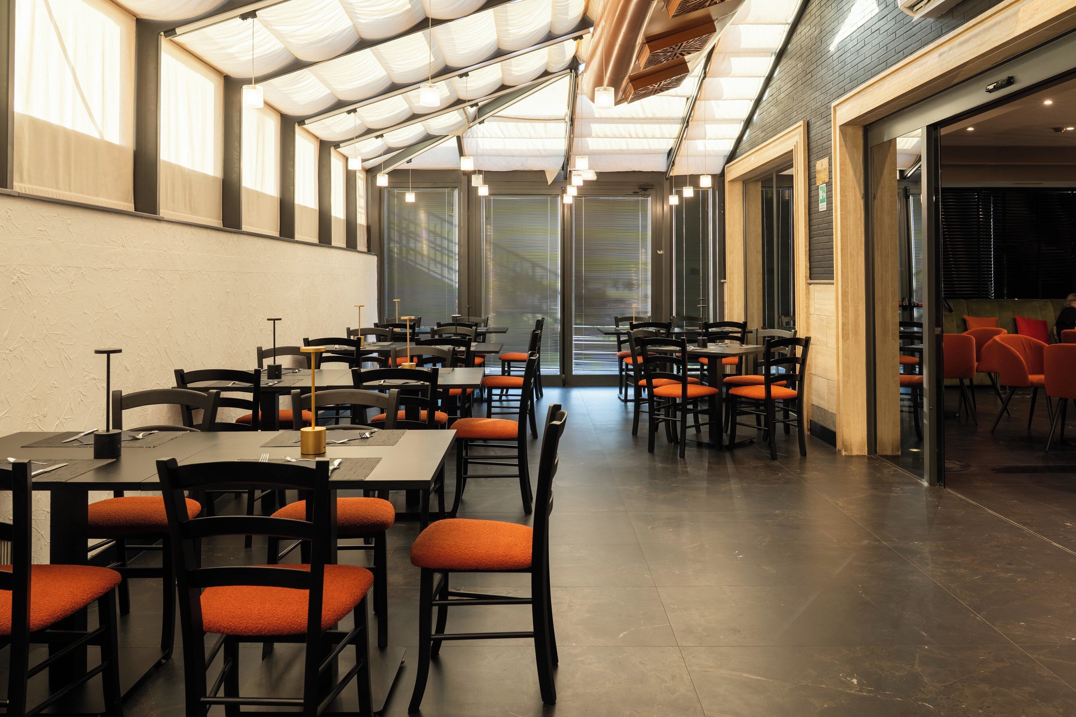 Een ruim restaurant met hoge plafonds, grote ramen en een modern interieur.