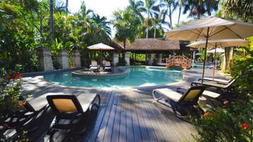 Relax by the serene pool surrounded by lush vegetation and shaded lounge areas.