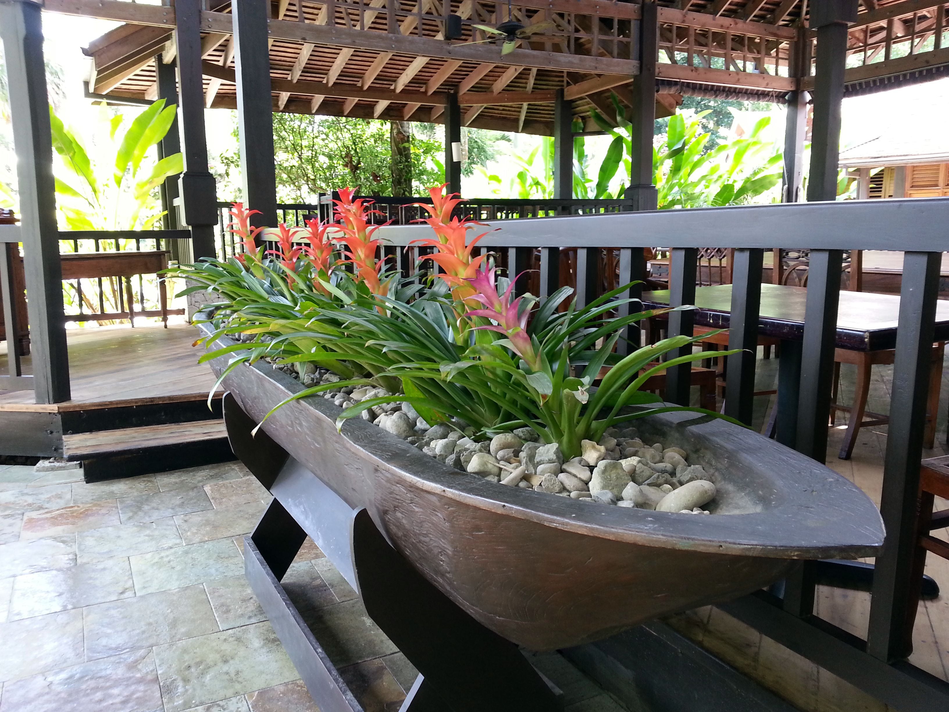 A covered outdoor seating area with a planter filled with plants and a wooden table.