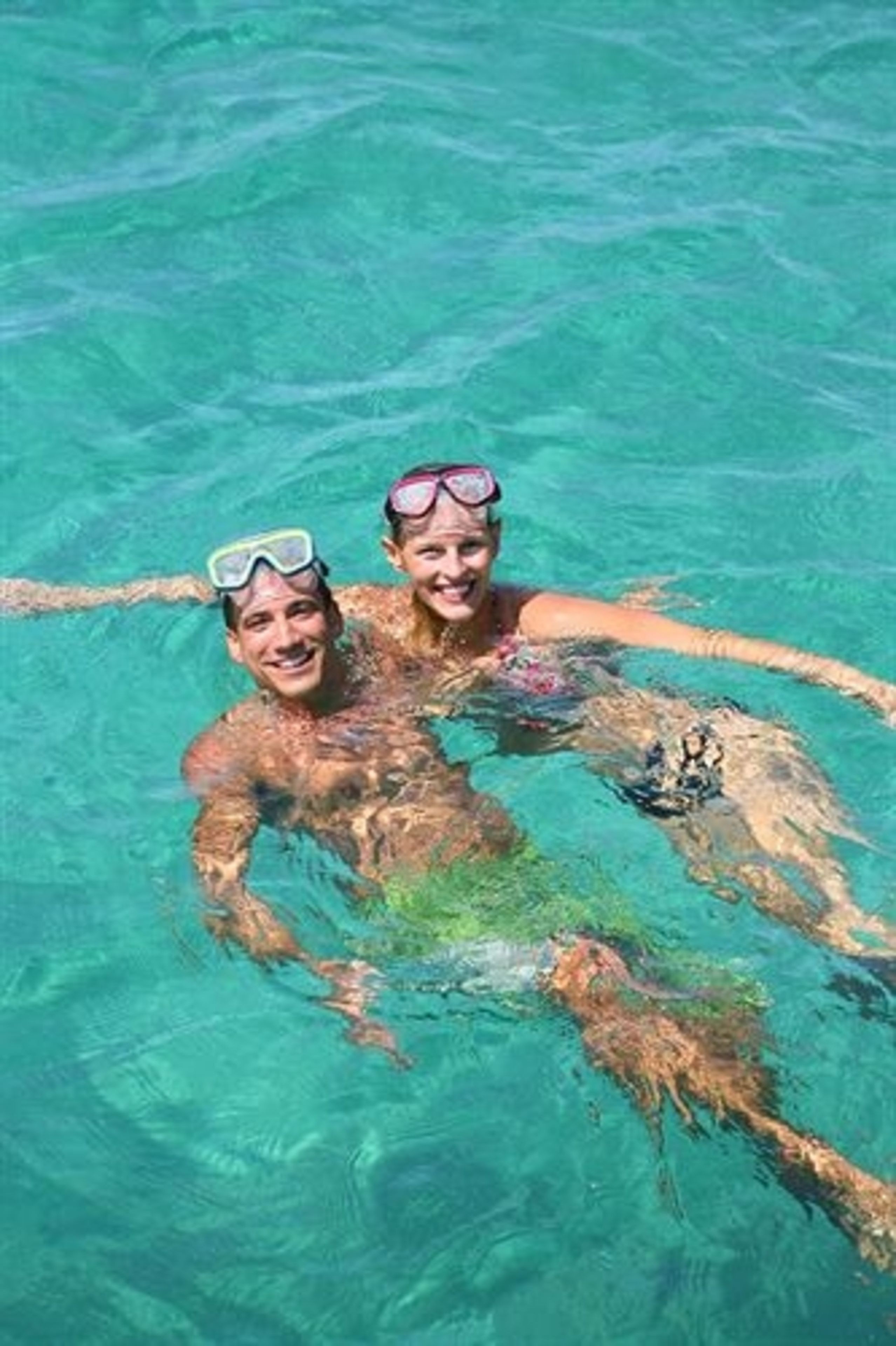Two people swimming in clear blue water.