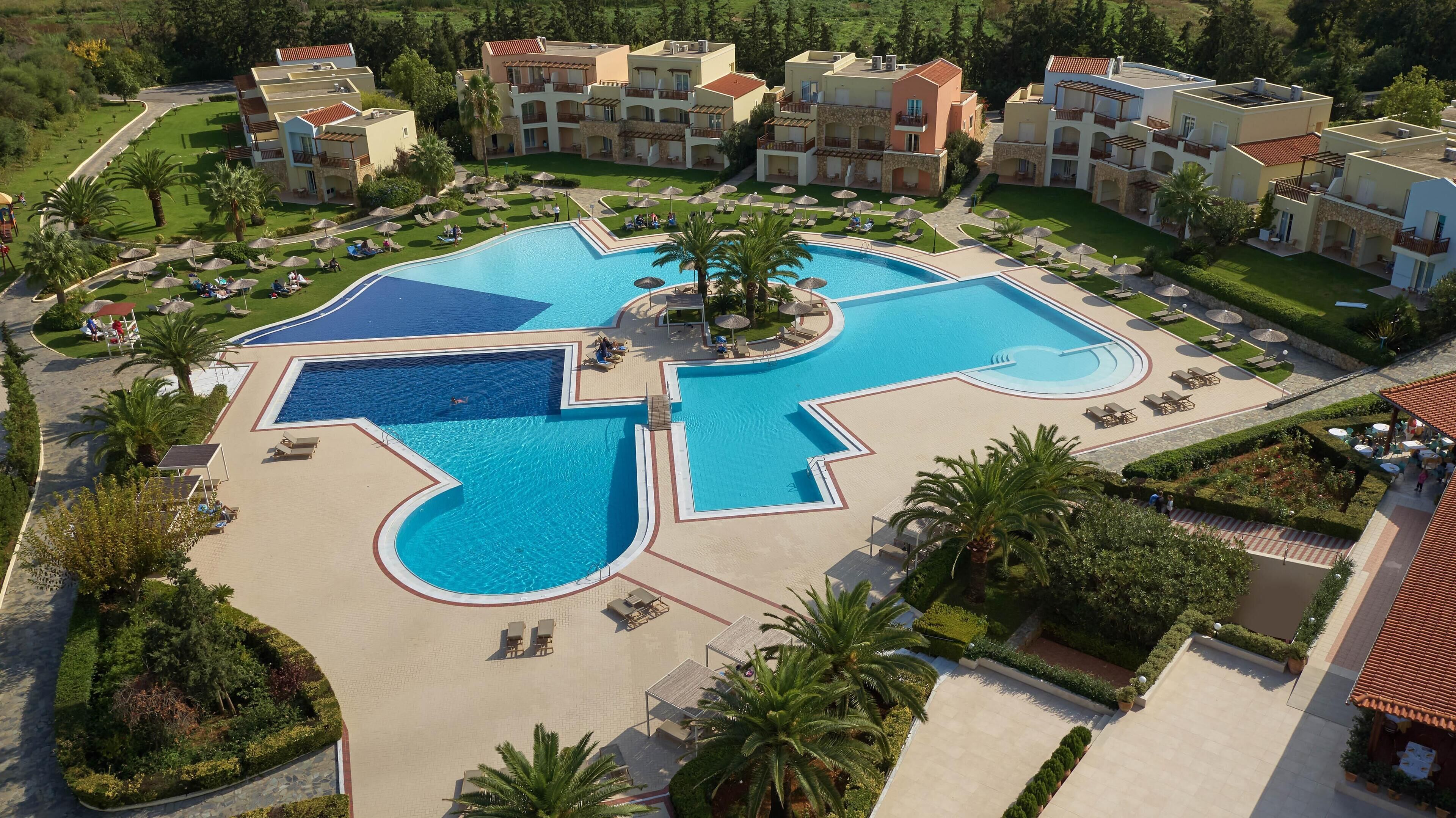 A resort with multiple swimming pools, sun loungers, and palm trees.