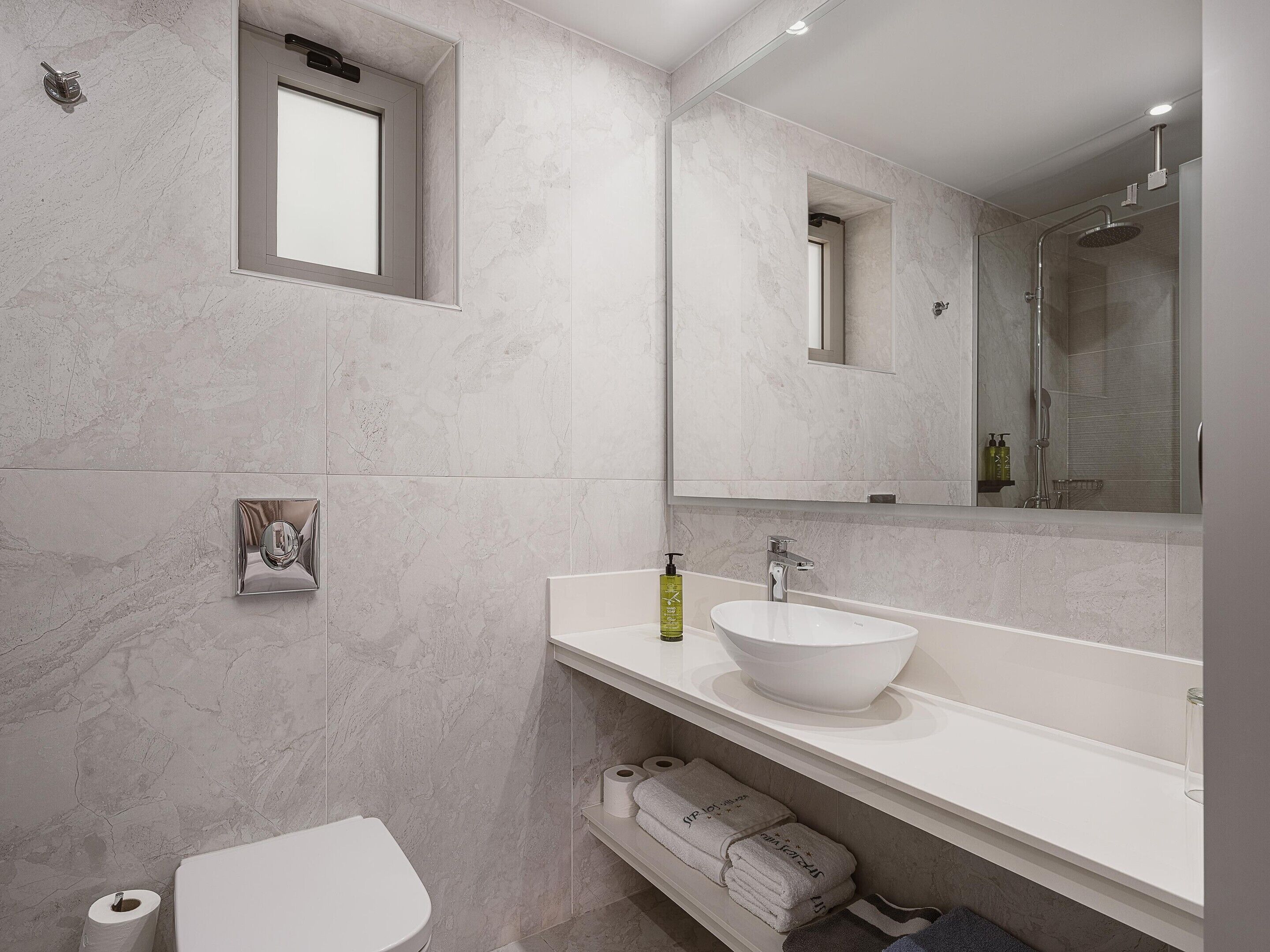 A modern bathroom with a white sink, a mirror, and a toilet.