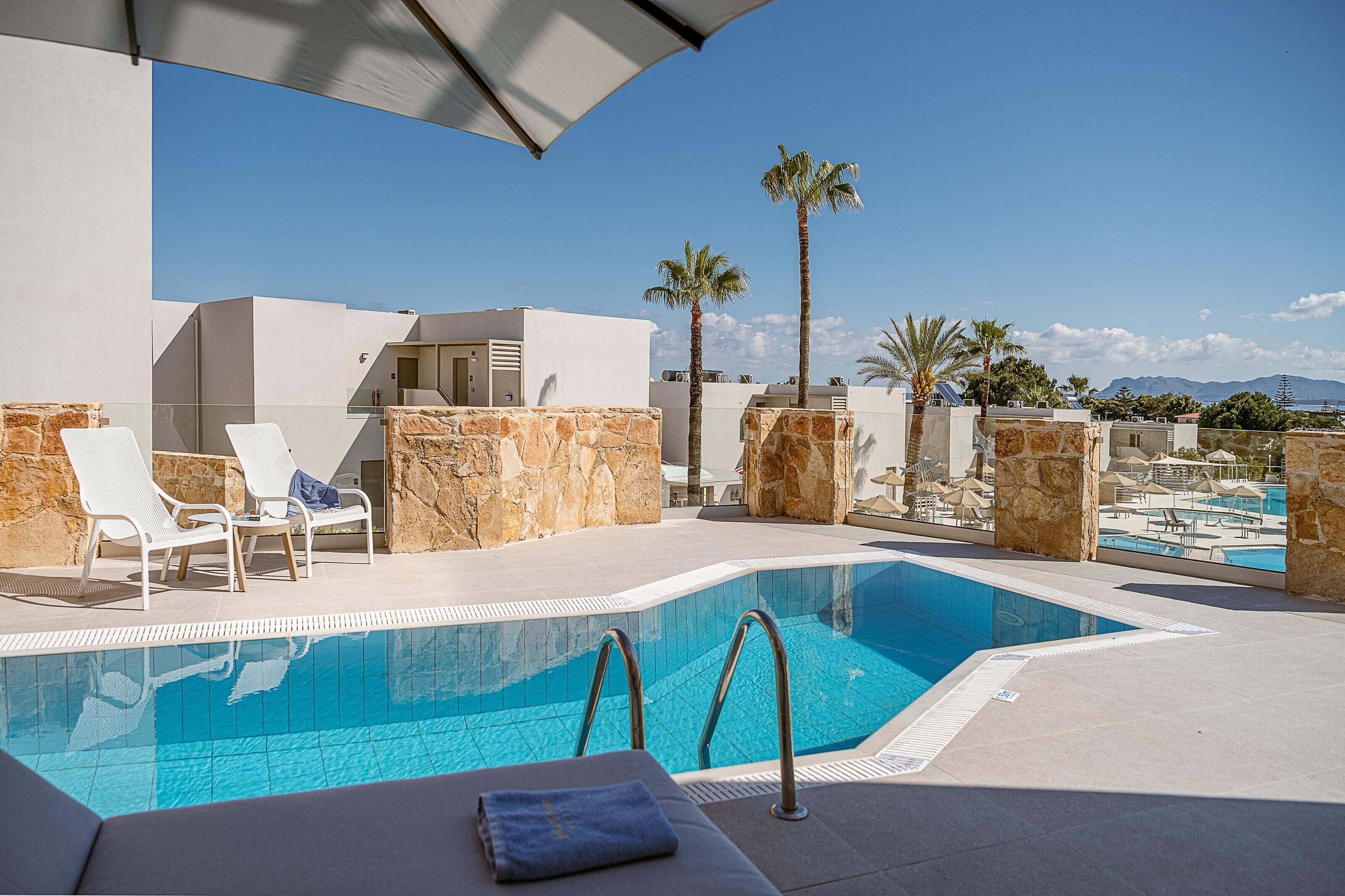 A rooftop pool area with lounge chairs, a swimming pool, and a view of the cityscape.