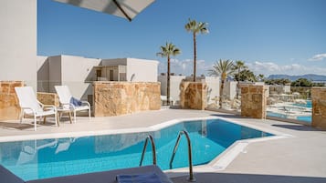 Un área de piscina en la azotea con sillones de descanso, piscina y vistas a la ciudad.