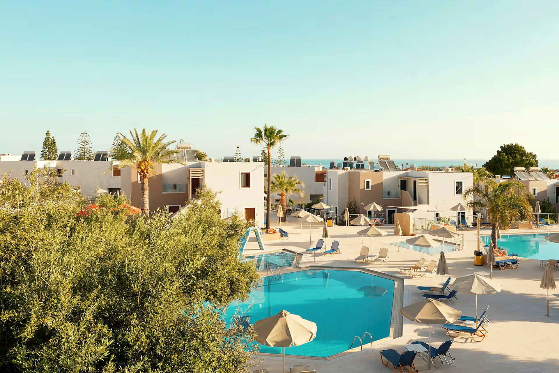 A resort with multiple swimming pools, lounge chairs, and palm trees.
