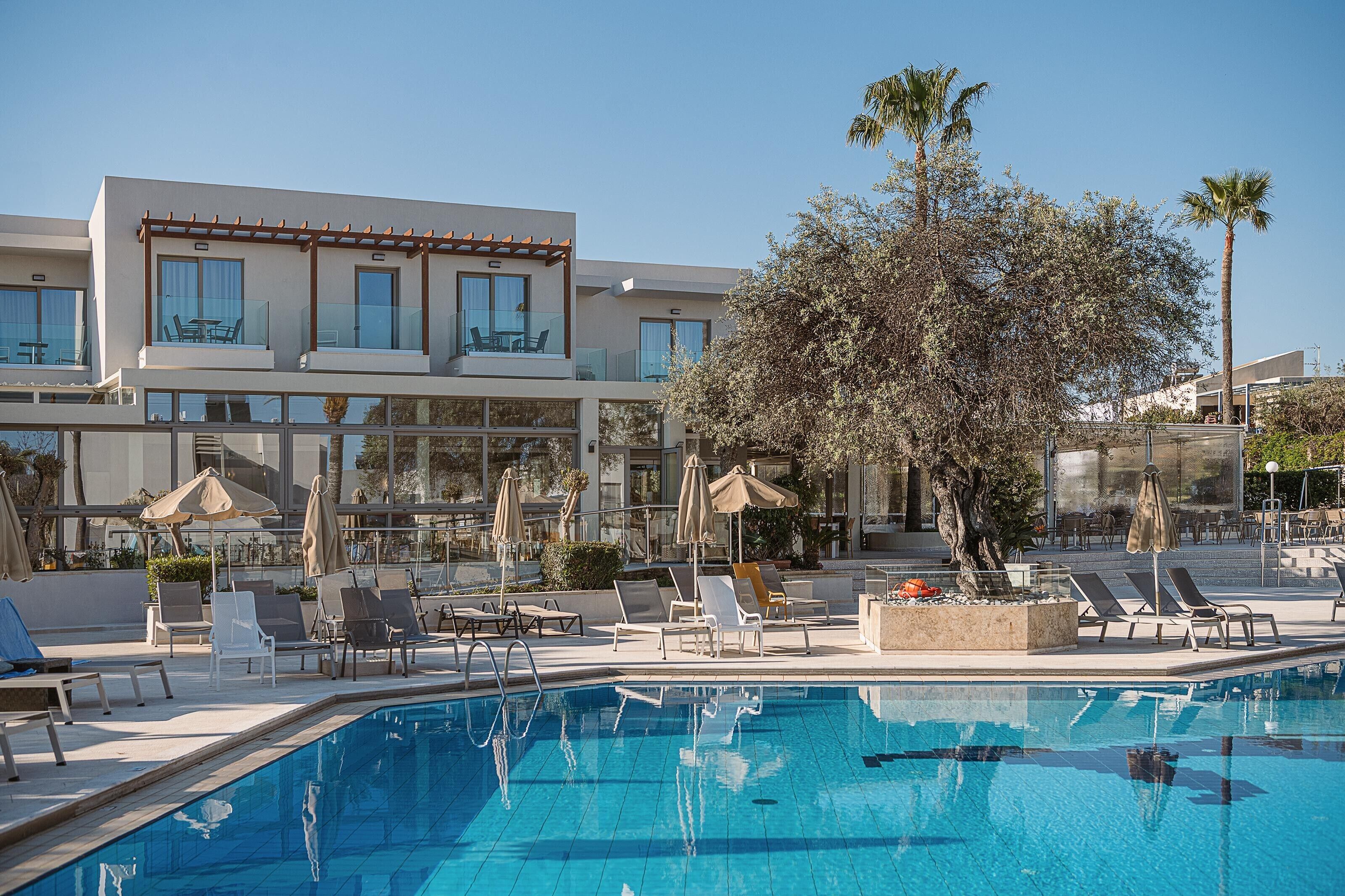 Un hotel moderno con piscina, area relax all'aperto e un grande albero.