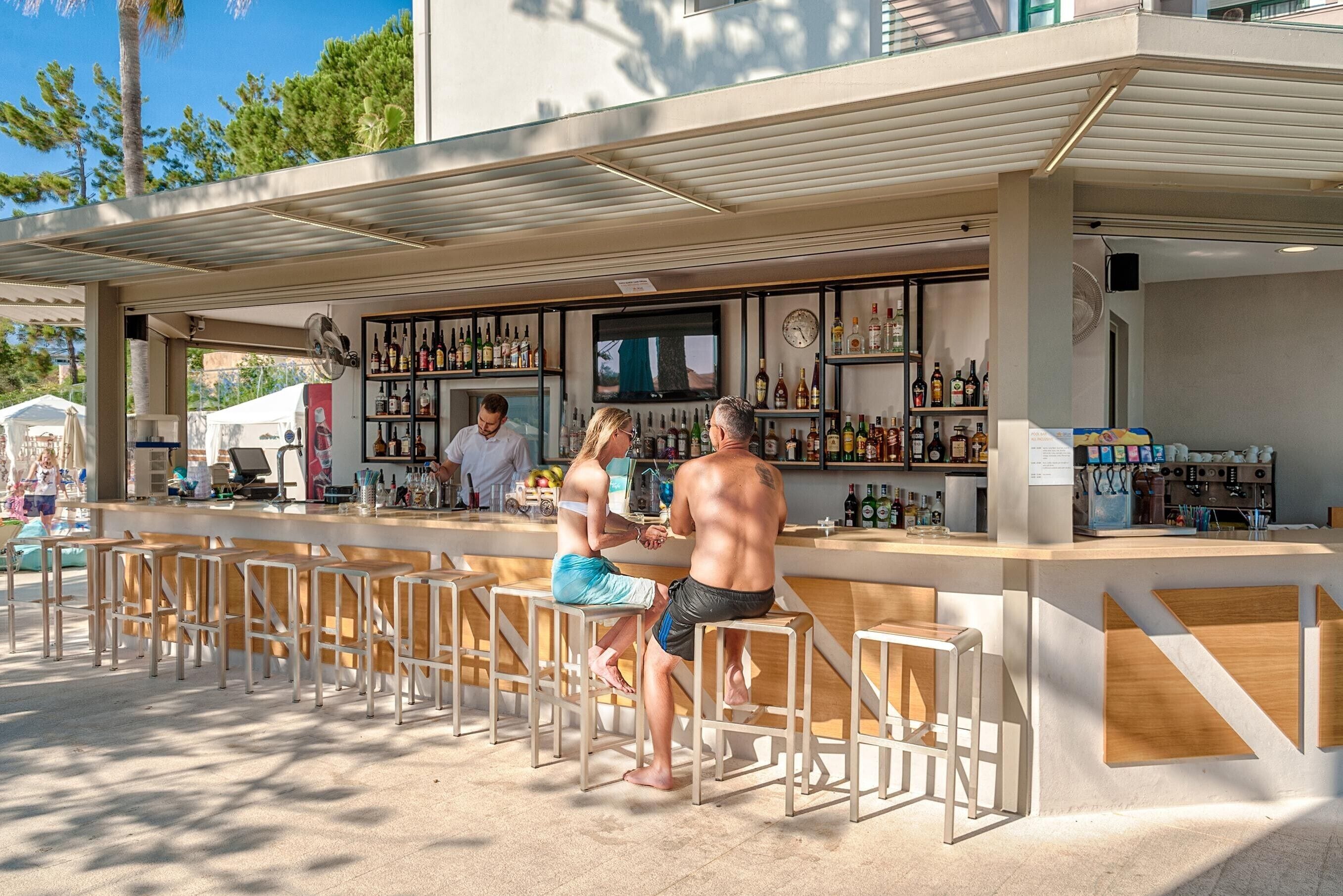 Ein Außenbereich mit Bar, einer Theke, Sitzgelegenheiten und einer Auswahl an Flaschen.
