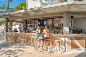 An outdoor bar area with a counter, seating, and a variety of bottles.