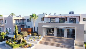 Un edificio moderno con entrada de vidrio, terraza en la azotea y jardín ajardinado.