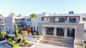 A modern building with a glass entrance, a rooftop terrace, and a landscaped garden. - Sirios Village Hotel & Bungalows - All Inclusive (Chania)