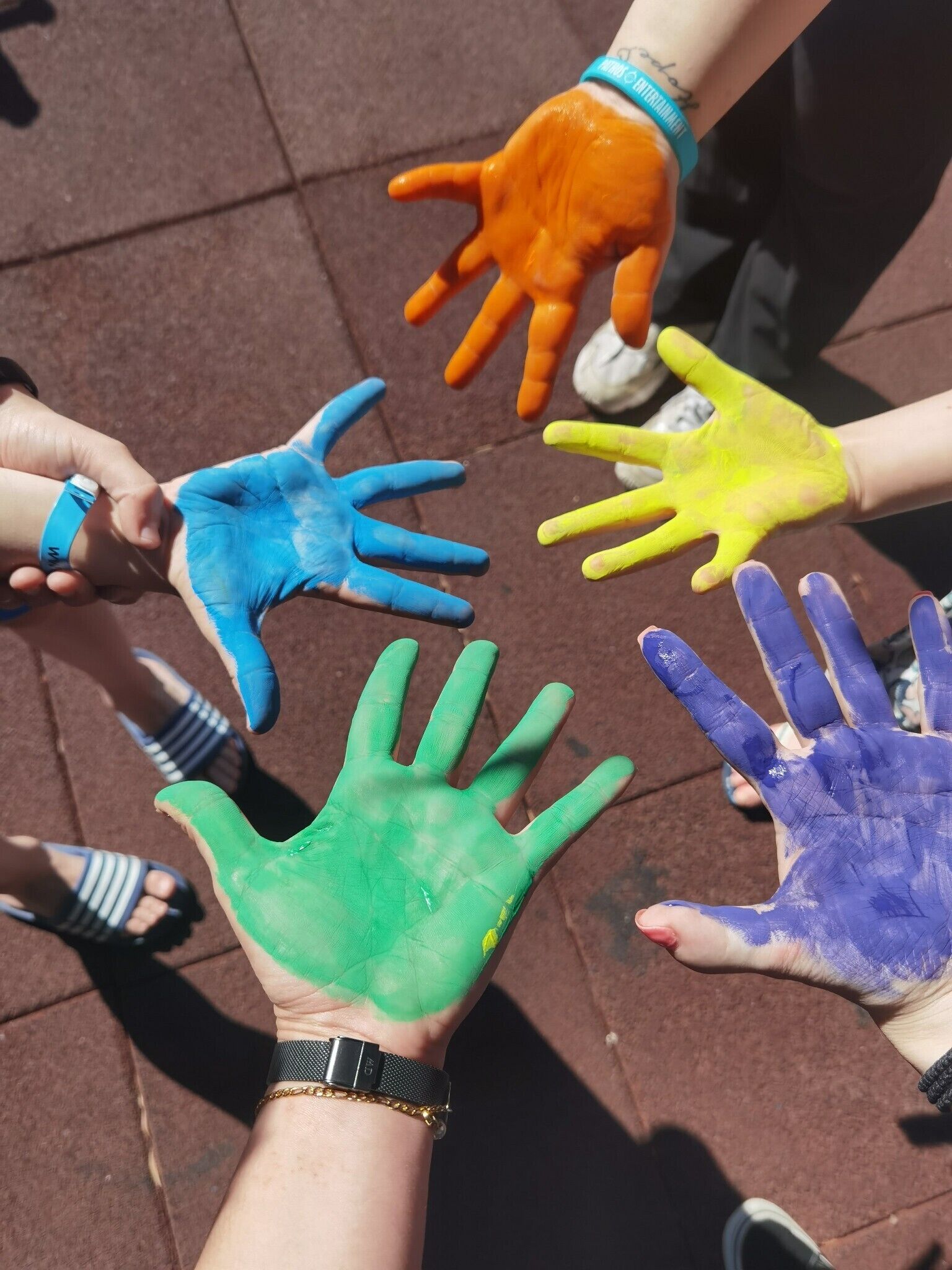 A group of hands painted in various colors reaching towards each other.