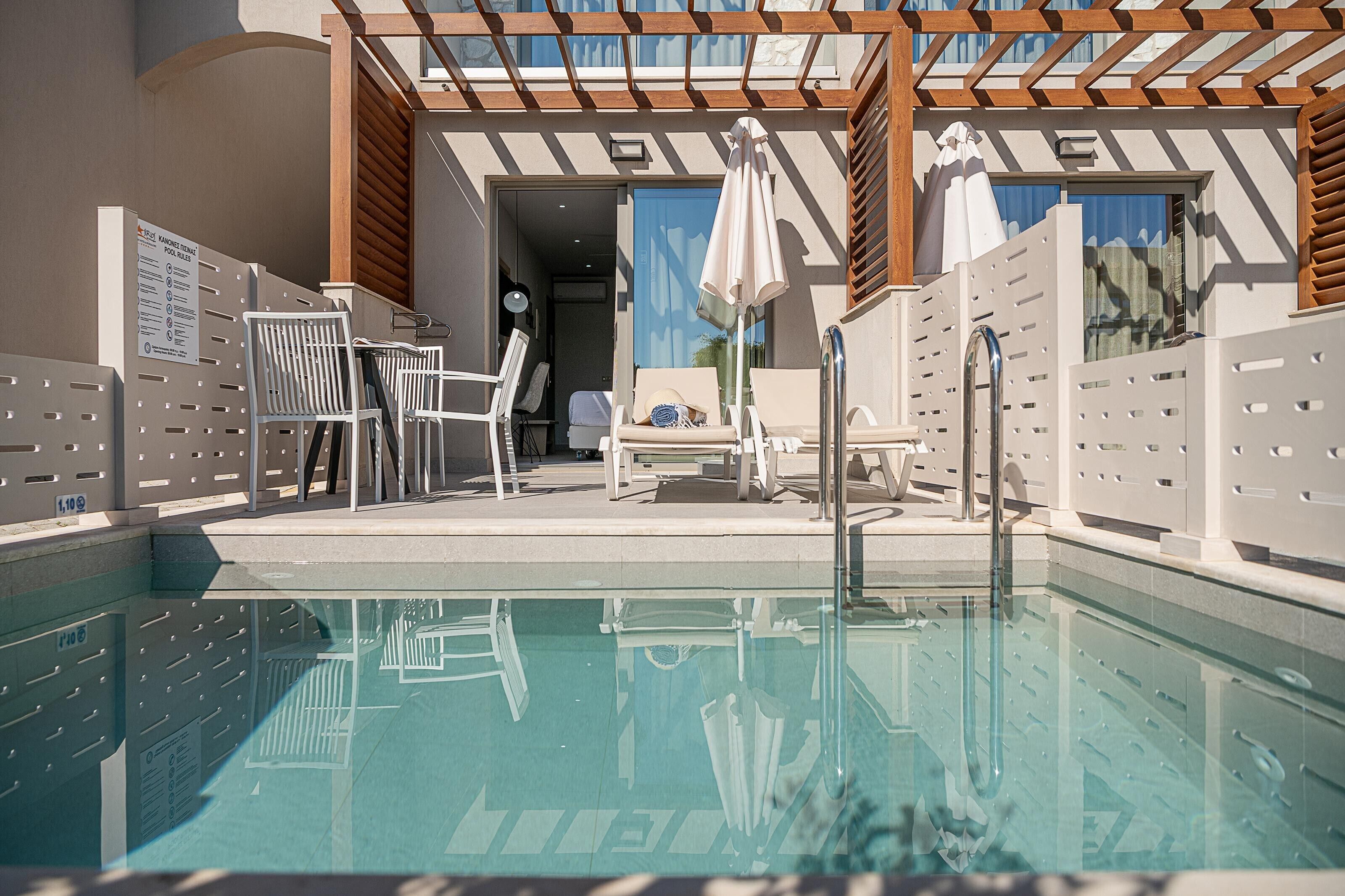 A pool area with a clear pool, lounge chairs, and a pergola structure.