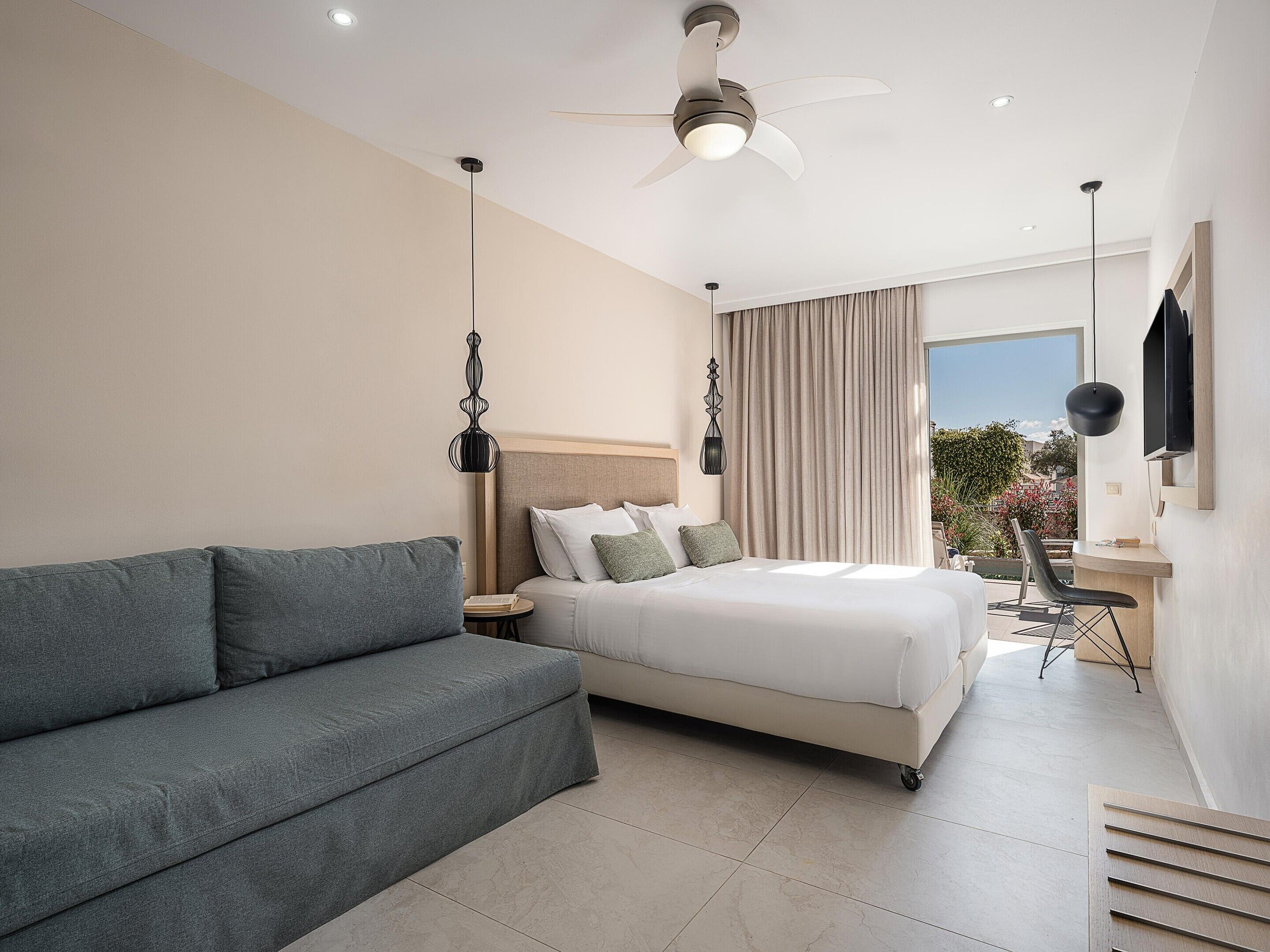 Un dormitorio moderno con cama, sofá, escritorio y ventilador de techo.