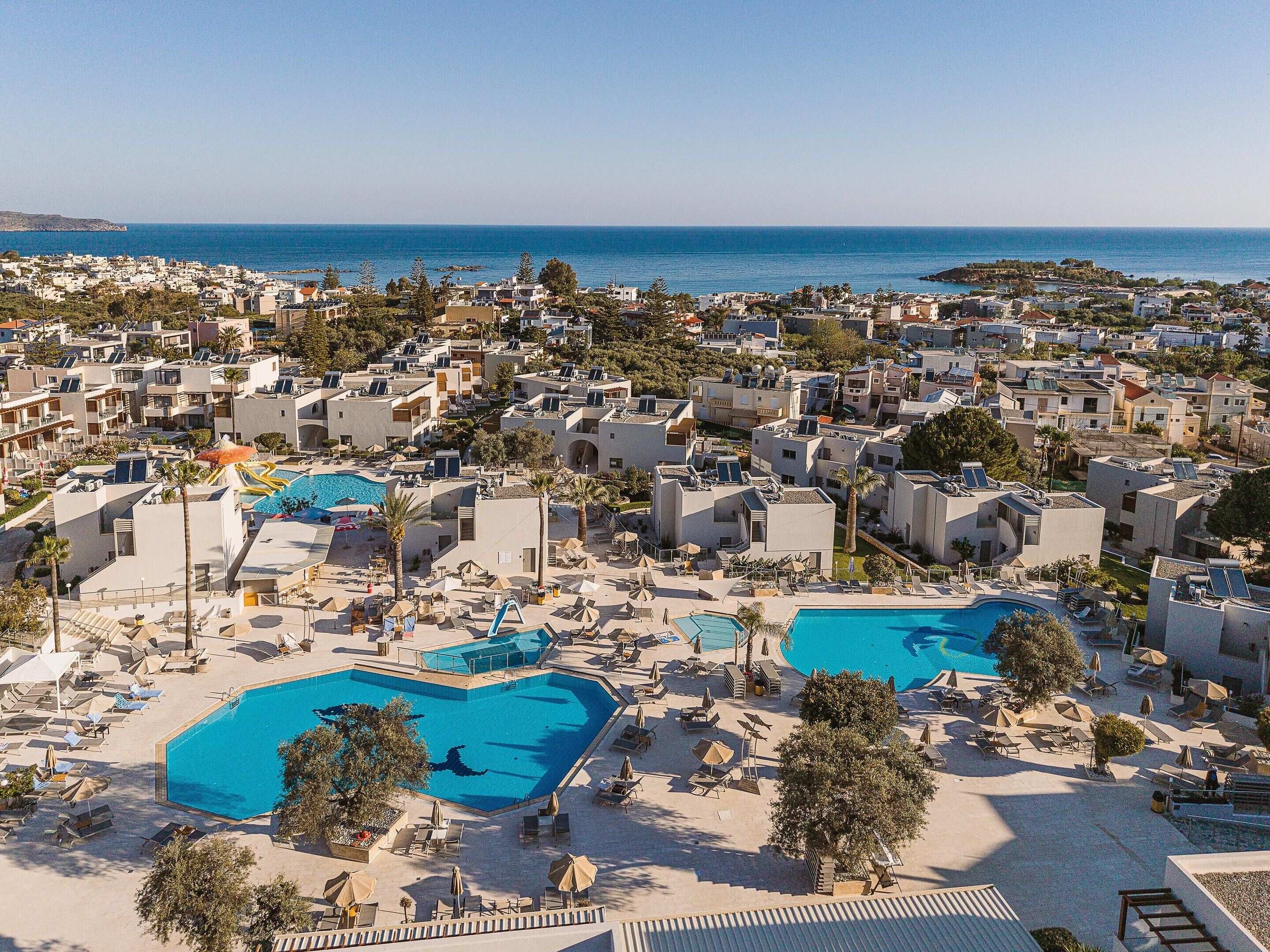 Ein Resort mit mehreren Schwimmbecken, Liegestühlen und Blick auf das Meer.