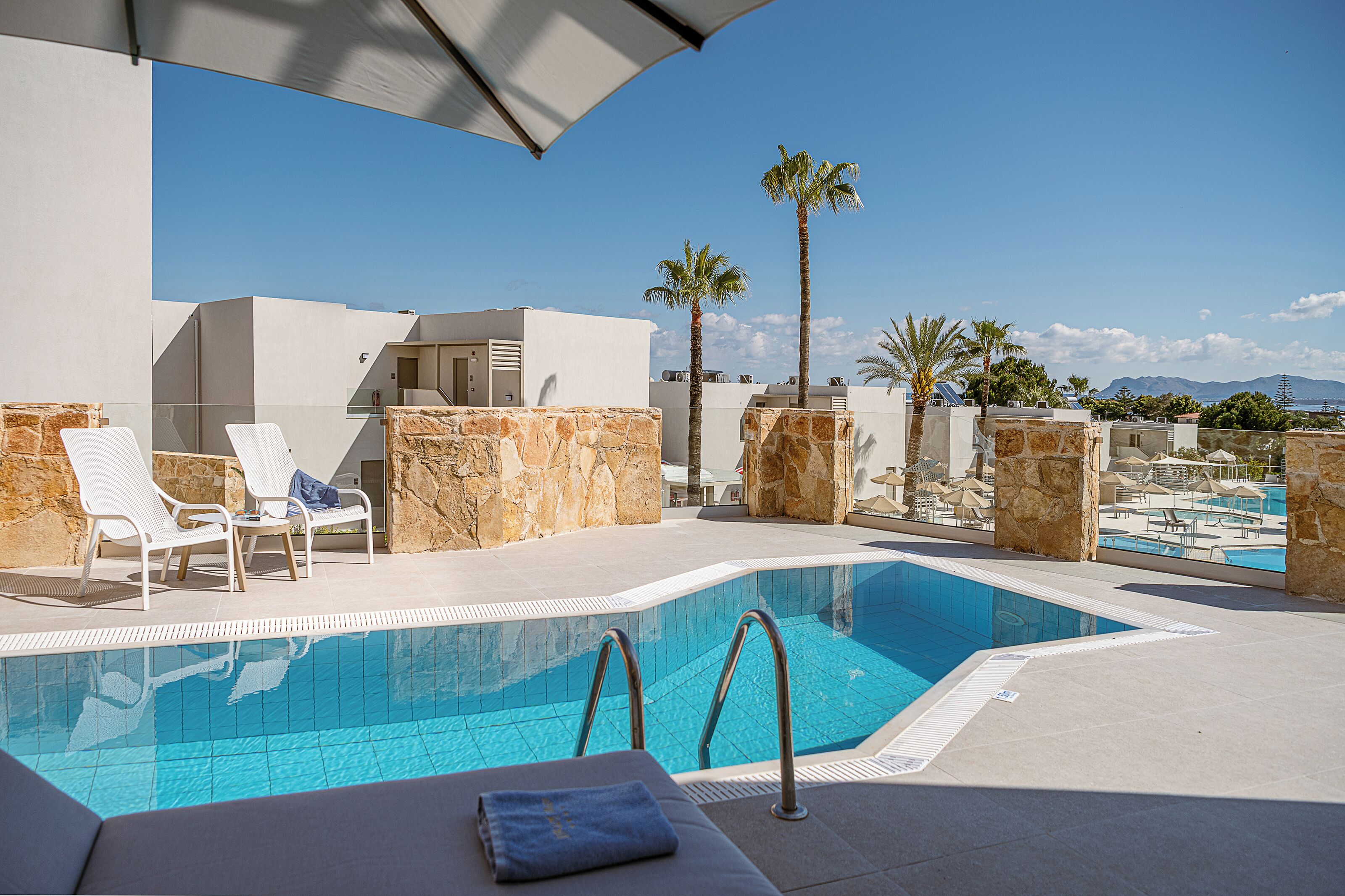 A rooftop pool with lounge chairs and a clear view of the mountains.