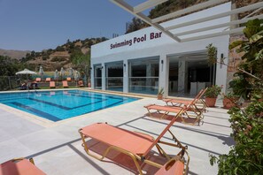 A swimming pool bar with lounge chairs and a pool. - Petra Hotel (Agios Vasileios)