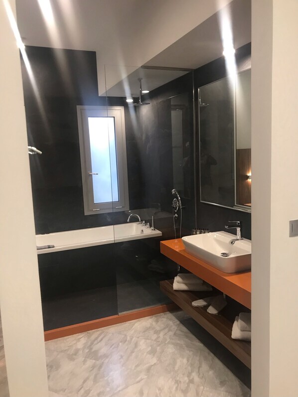 A modern bathroom with a large mirror, two sinks, and a shower. - Petra Hotel (Agios Vasileios)