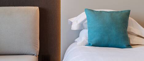 A modern bedroom with a bed, a bedside table, and a hanging light fixture.