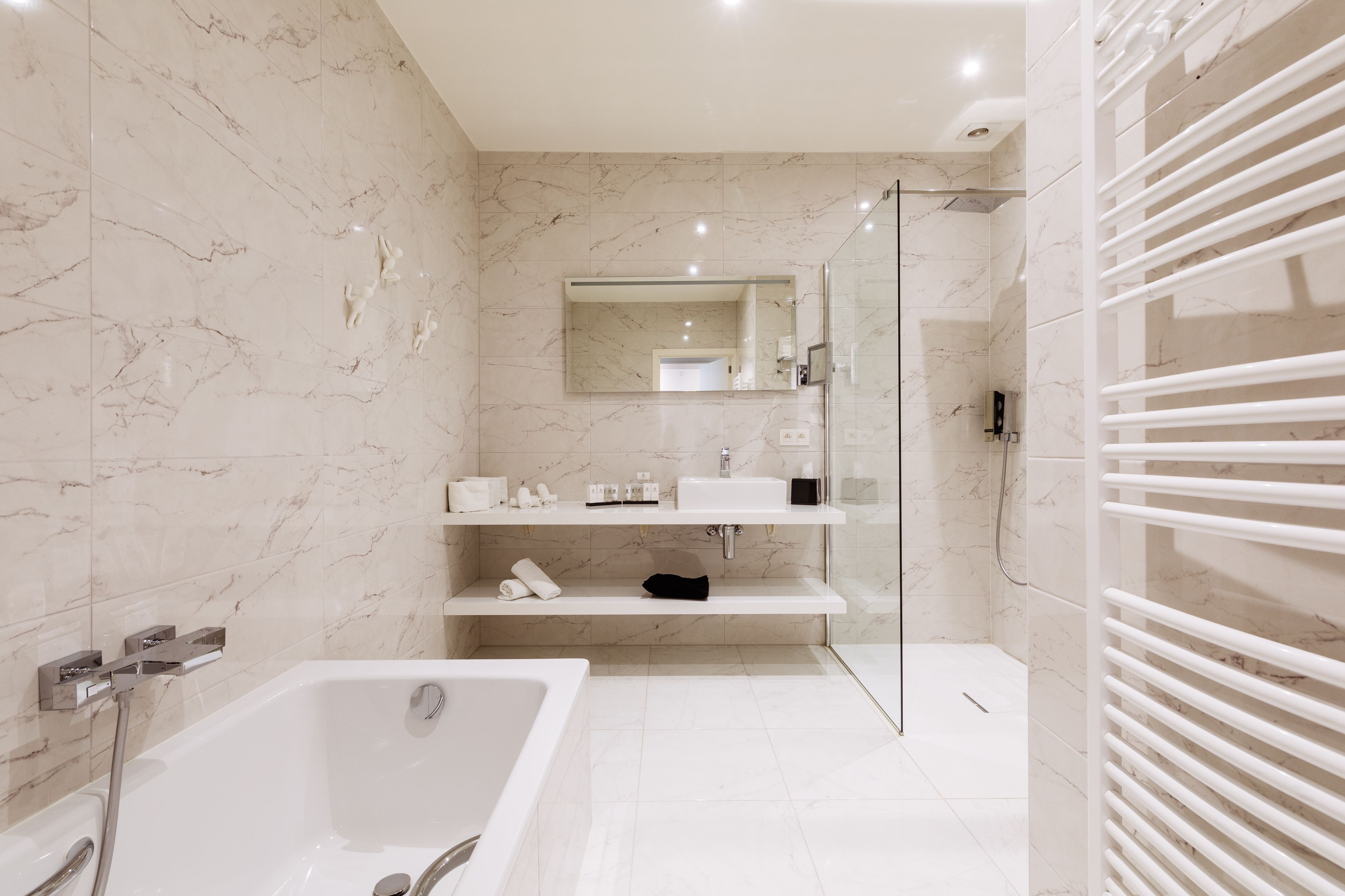 Een moderne badkamer met een groot bad, een glazen douchecabine en marmeren wanden.