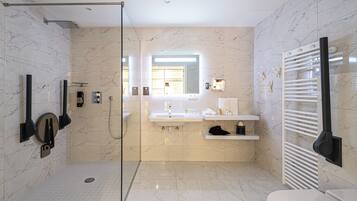 Un baño moderno con cabina de ducha de vidrio, un espejo grande, un lavabo con tocador y un perchero para toallas.