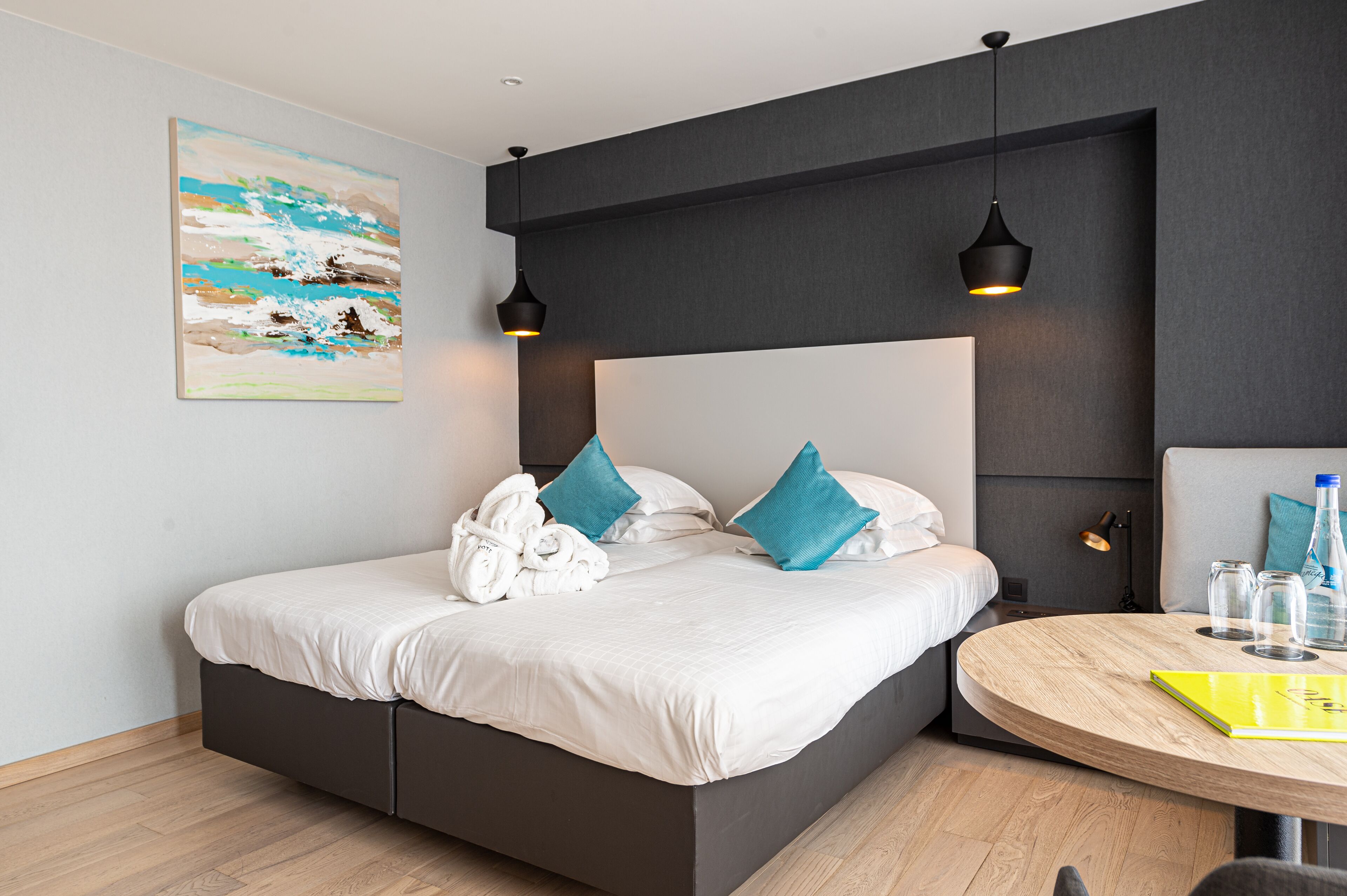 Una camera d'albergo moderna con un letto, un tavolino rotondo e un quadro appeso al muro.