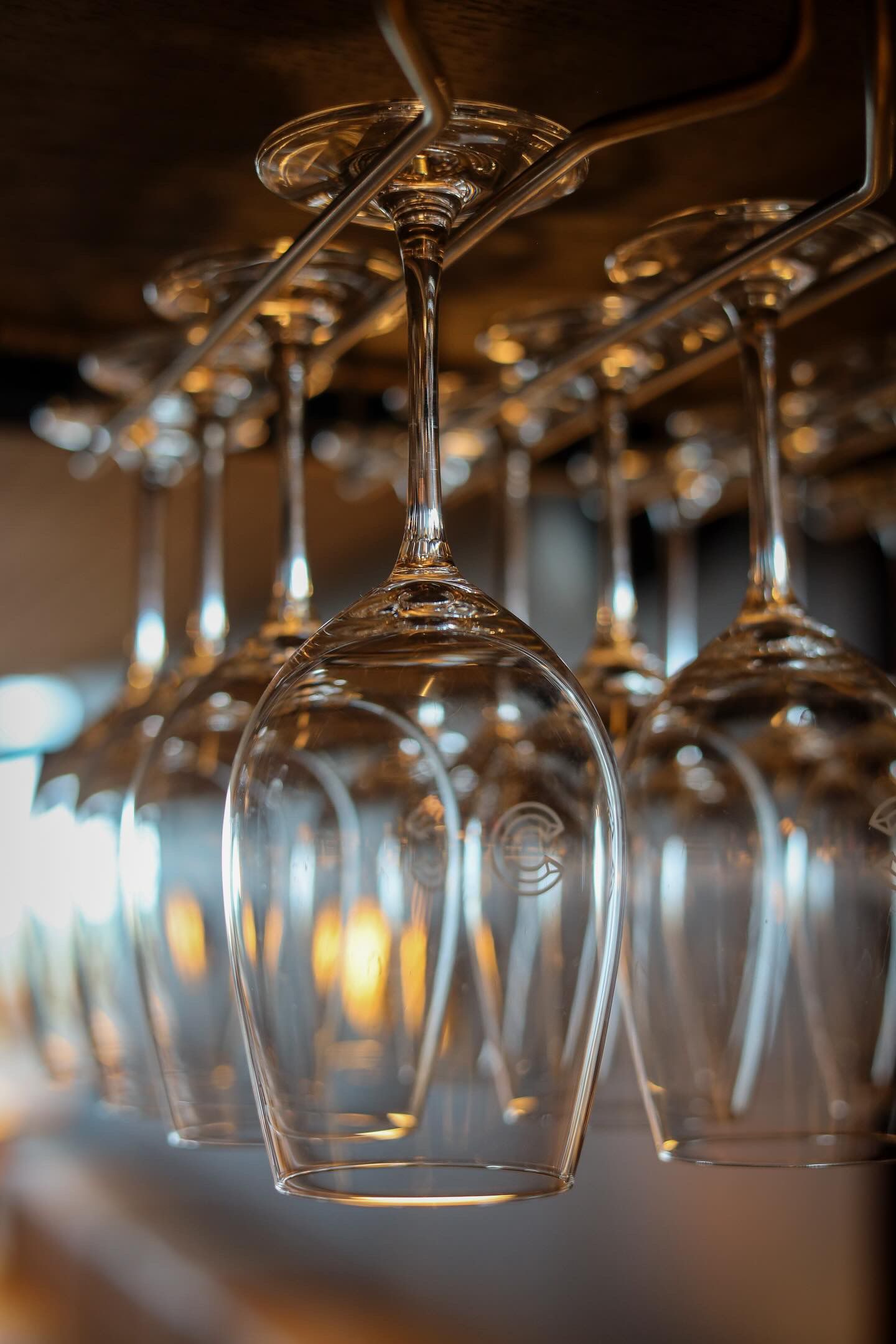A row of empty wine glasses hanging from a ceiling.